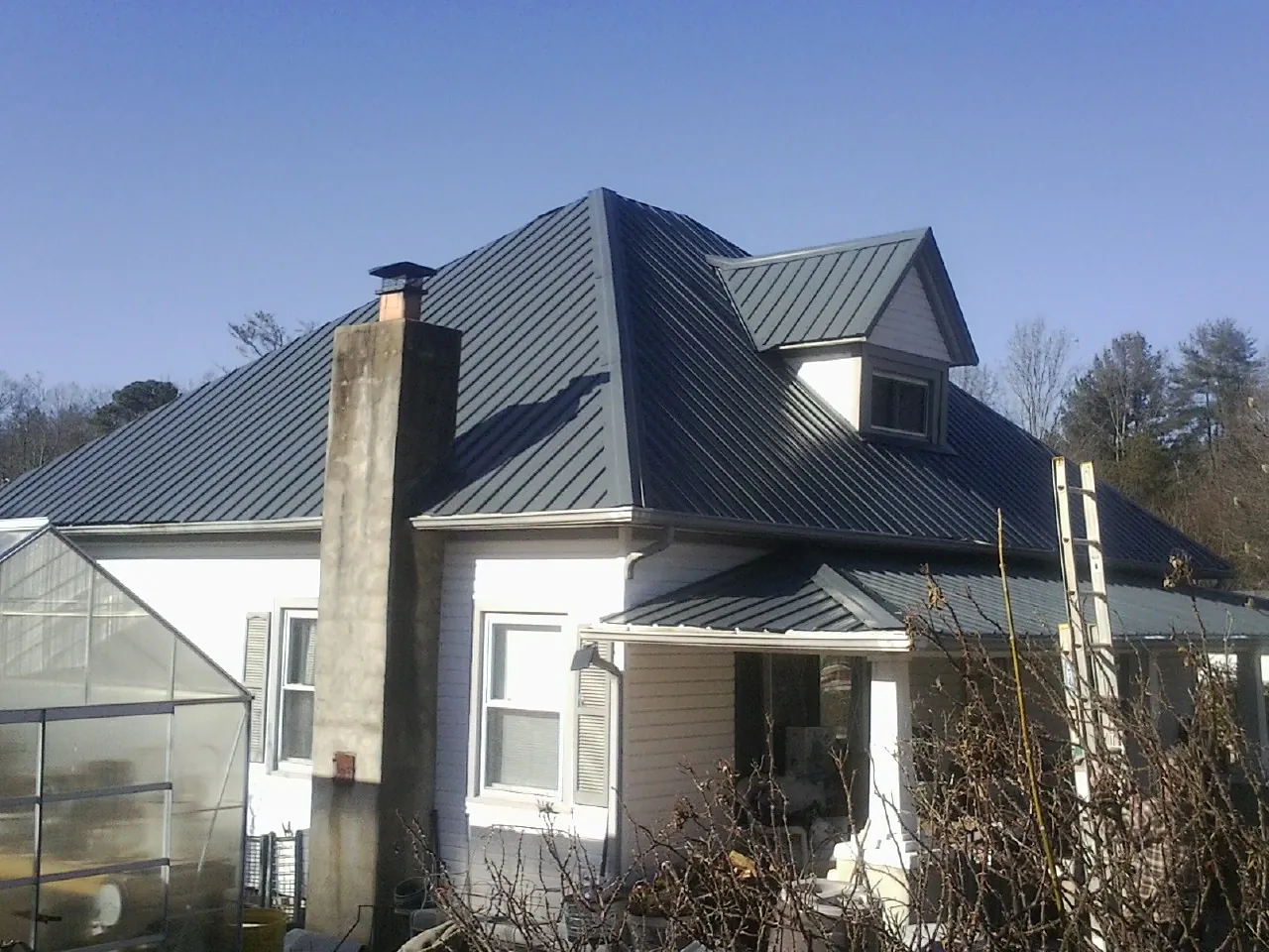 Dark blue standing seam metal roof on a white farmhouse with dormer — Slate & Tile Roof Repair by Roofing Brothers in Bonners Ferry