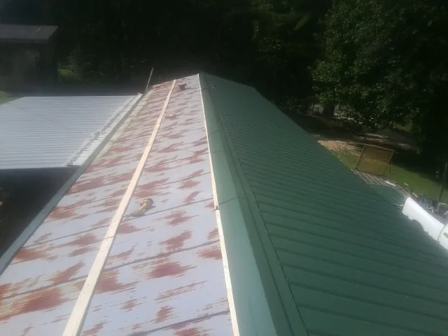 Old rusted panels beside newly installed green metal roofing — Wind Damage Roof Repair by Roofing Brothers in Bonners Ferry