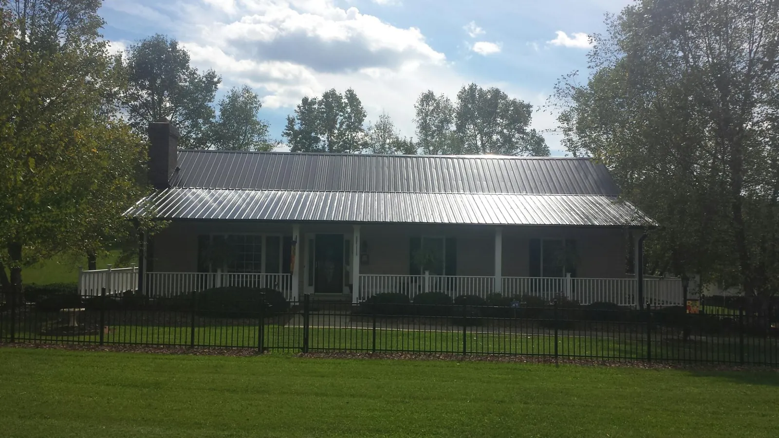 Gray metal roof on a brick ranch with a full width front porch — Gutter Guard Installation work by our crew in Bonners Ferry