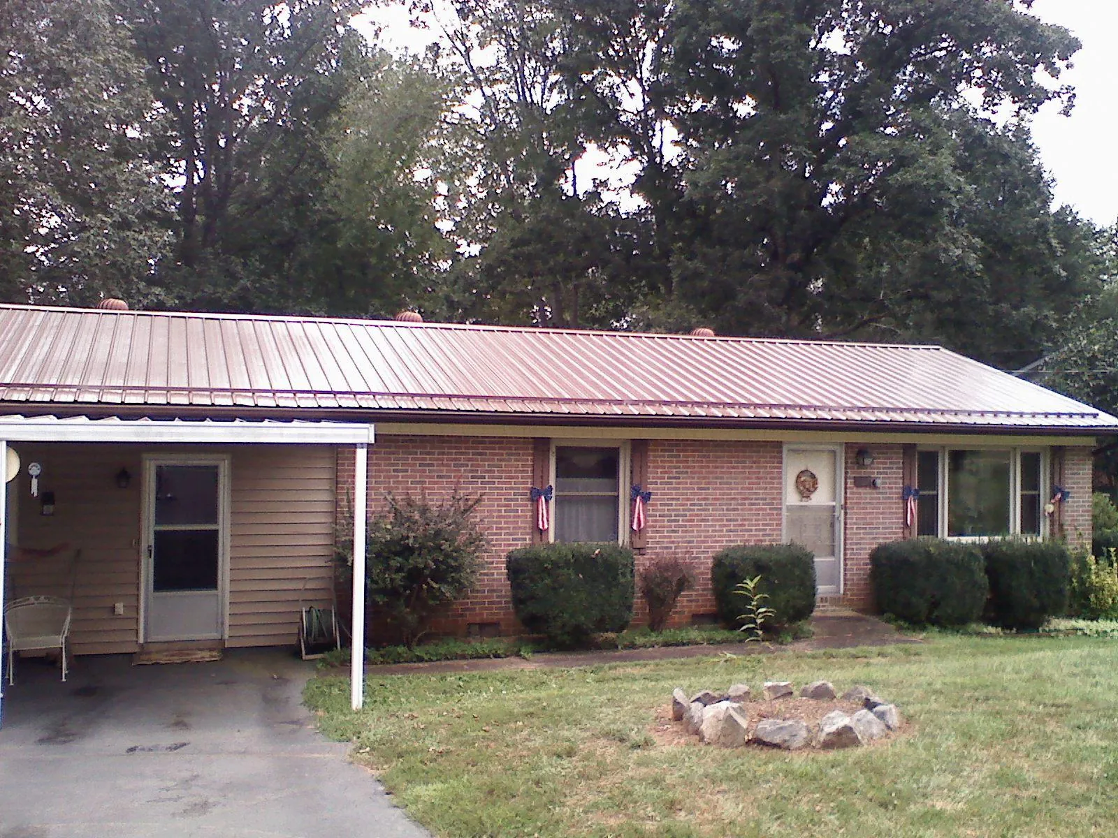 Bronze metal roof and carport on a brick ranch home — Roof Repair work by our crew in Bonners Ferry
