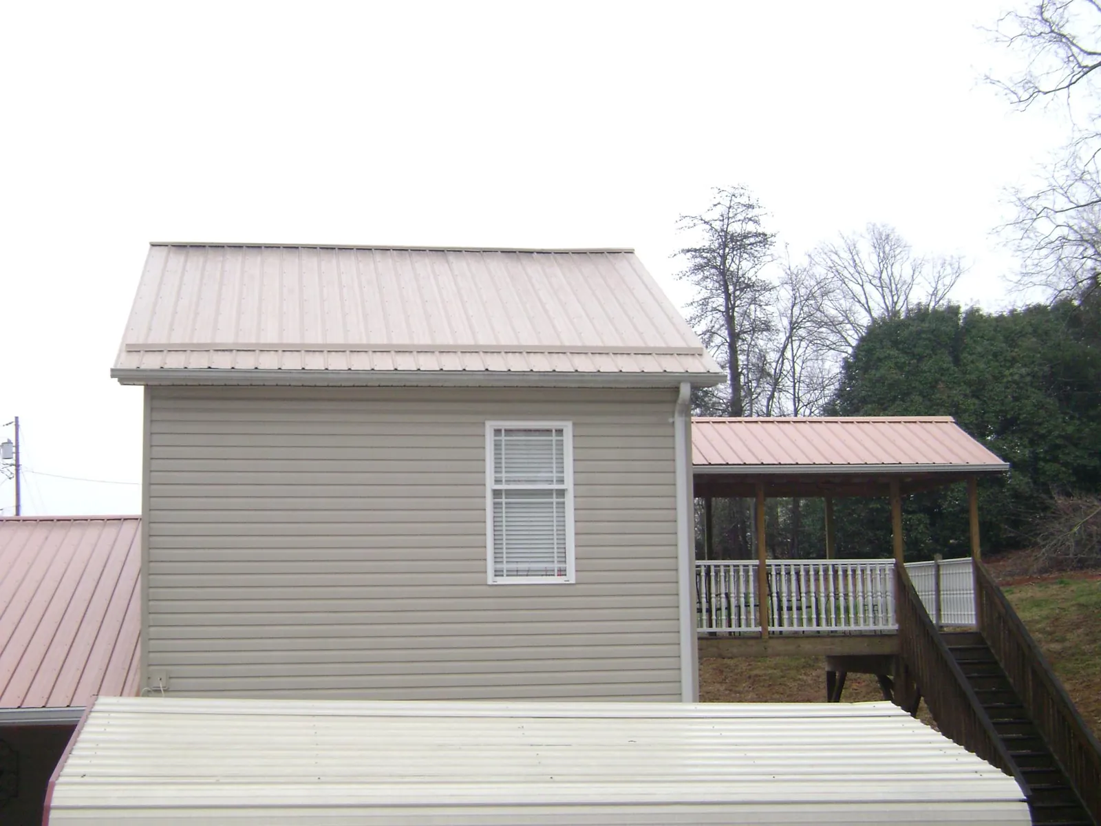 Tan metal roofs on a two story addition and attached porch, from a Roof Replacement job in Bonners Ferry