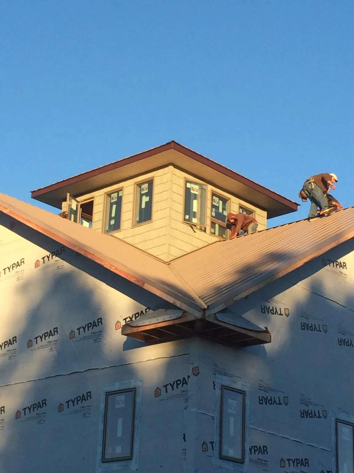 Roofers working around a rooftop cupola on a new metal roof at sunset — Roof Waterproofing in Bonners Ferry by Roofing Brothers